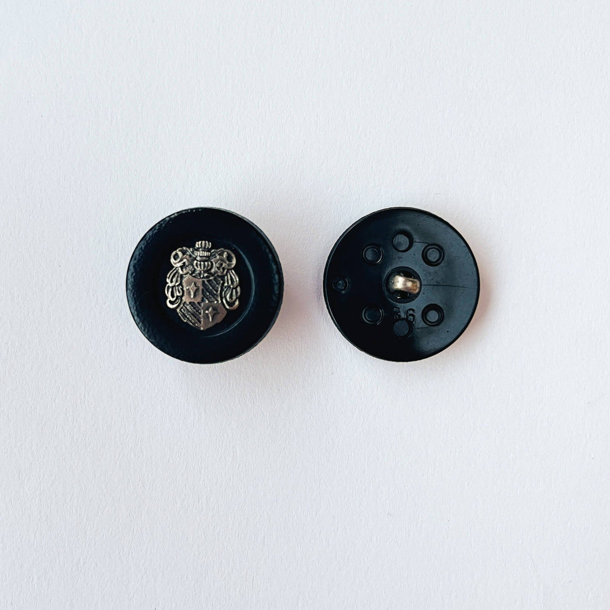 close up of 36 line, 23mm Crested Military Button with heraldic Coat of Arms Shield design on white background