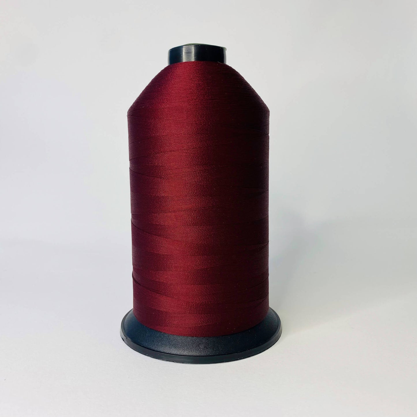 Spool of wine thread on a white background