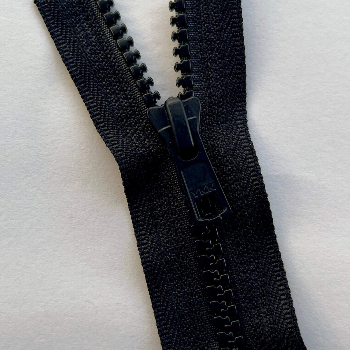 close up of YKK #5 Metal Vision Pullers and Continuous Black Vislon Zip Chain