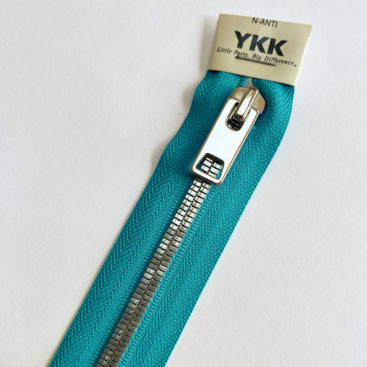 close up of Turquoise A YKK EXCELLA® Flat closed end zip with flat, smooth style silver metal teeth and decorative puller.