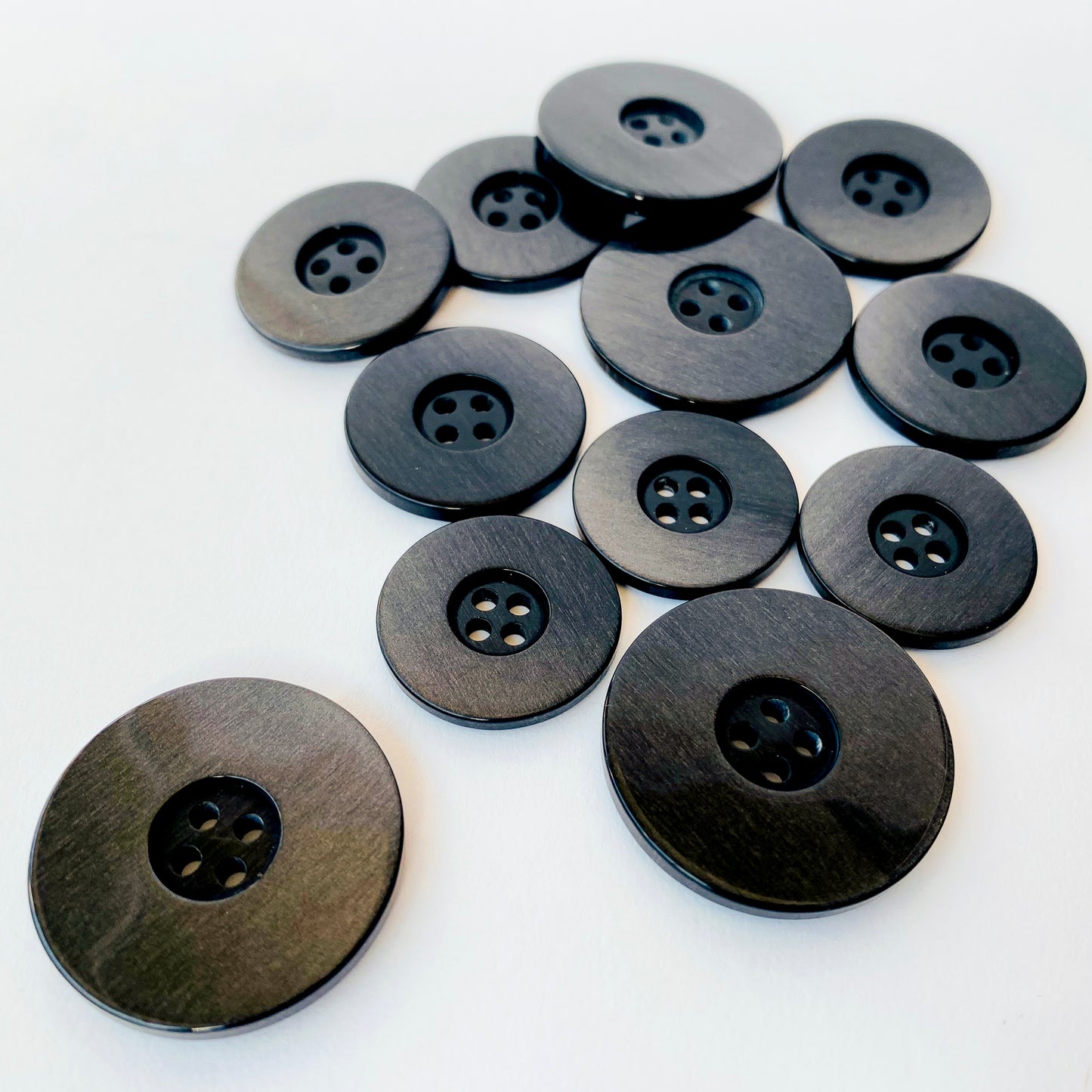 Black iridescent Buttons Luxury, high quality hand finished iridescent suiting buttons. Col: Black back with a pearlised luster finish to suit most dark fabrics Sizes: 36L (23mm), 40L (26mm), 48L (31mm) Origin: Italy / Deadstock