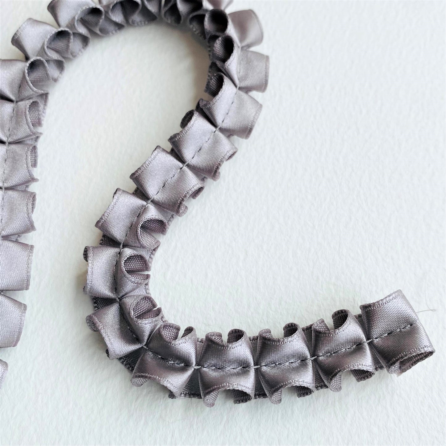 15mm Pleated Satin ribbon by MOKUBAA beautifully soft pleated satin ribbon trim by Mokuba, carefully gathered, held together by a single stitch running through the middle, which comes in two beautiful colours. silver, grey, gunmetal ribbon