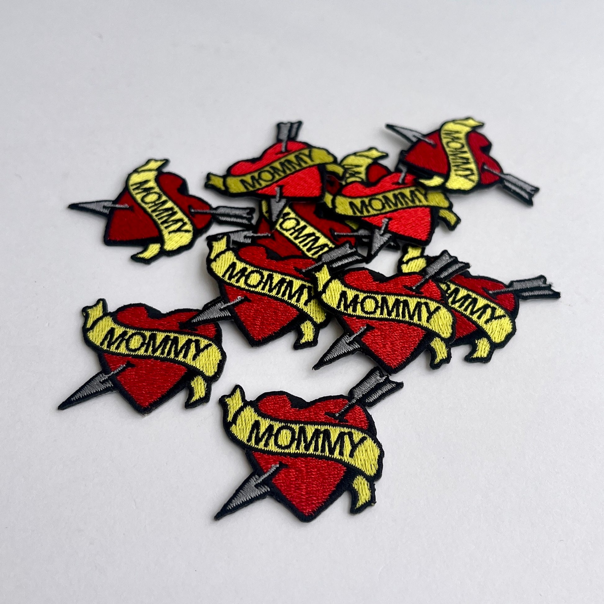 Cute patch of a red heart and arrow wrapped in a 'Mommy' banner.