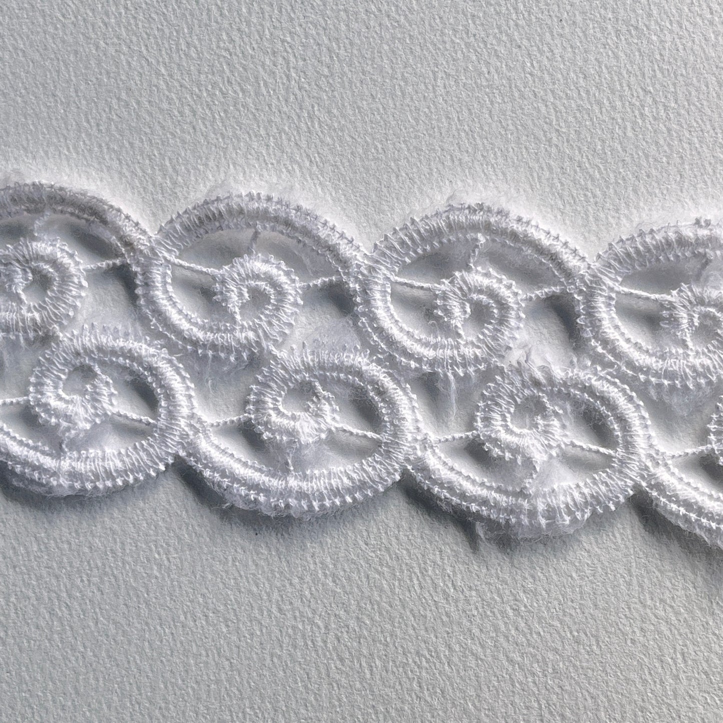 Off-white lace border trim with delicate scroll design and scalloped edge.