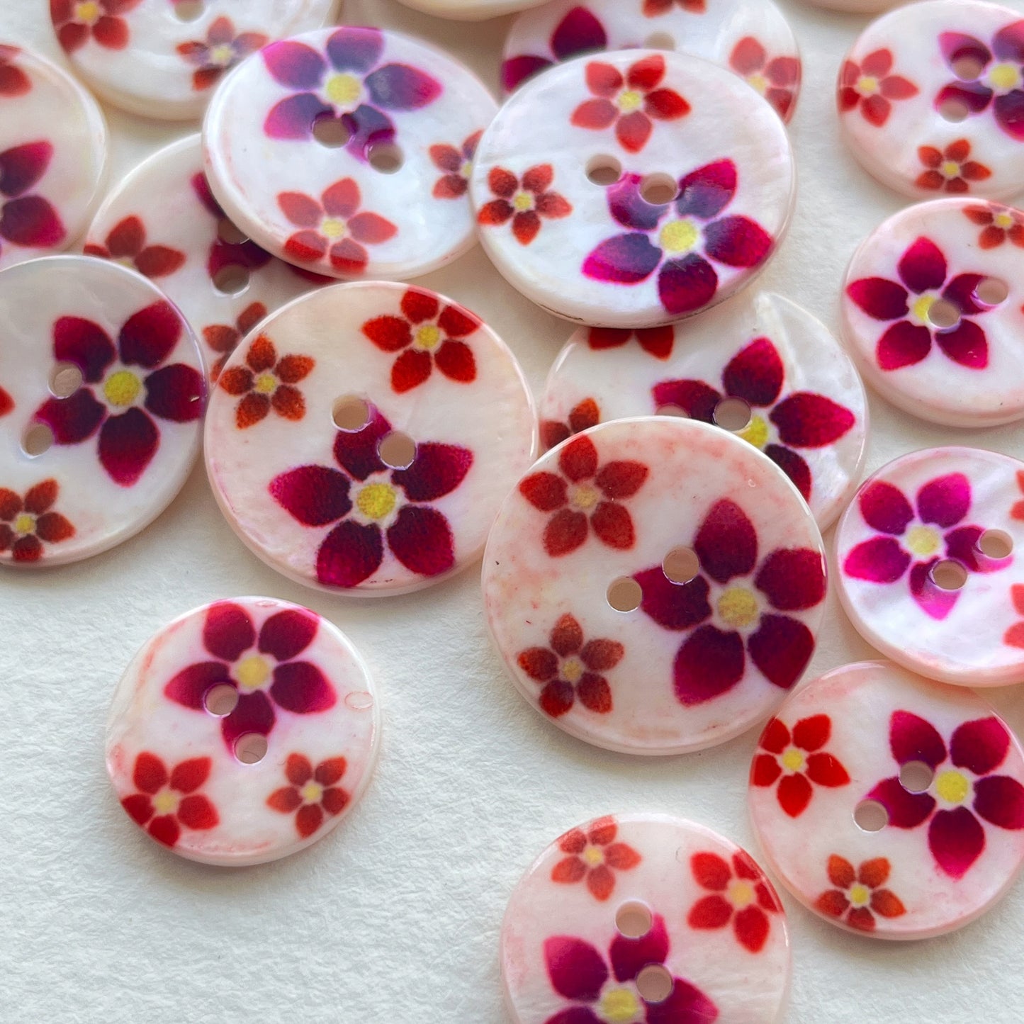 pretty lacquered Agoya shell buttons with floral design in red and pink. Deadstock haberdashery. Choose our range of vintage buttons, trims & sewing accoutrement rescued from a London haberdasher. Sew sustainably.