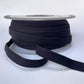 A spool of wide black elastic ribbon with a length of the ribbon unspooled in front, set against a plain white background.