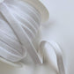 White satin bra elastic ribbon spool with a single loop of ribbon extending out on a clean white background.