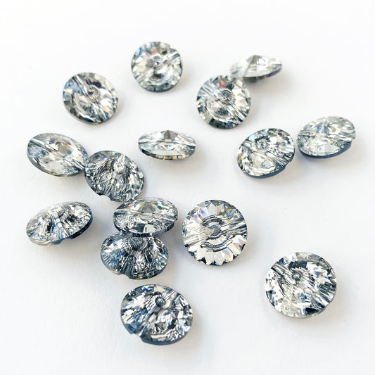 A collection of round Swarovski crystal buttons with a silver foil backing, displayed on a white background.