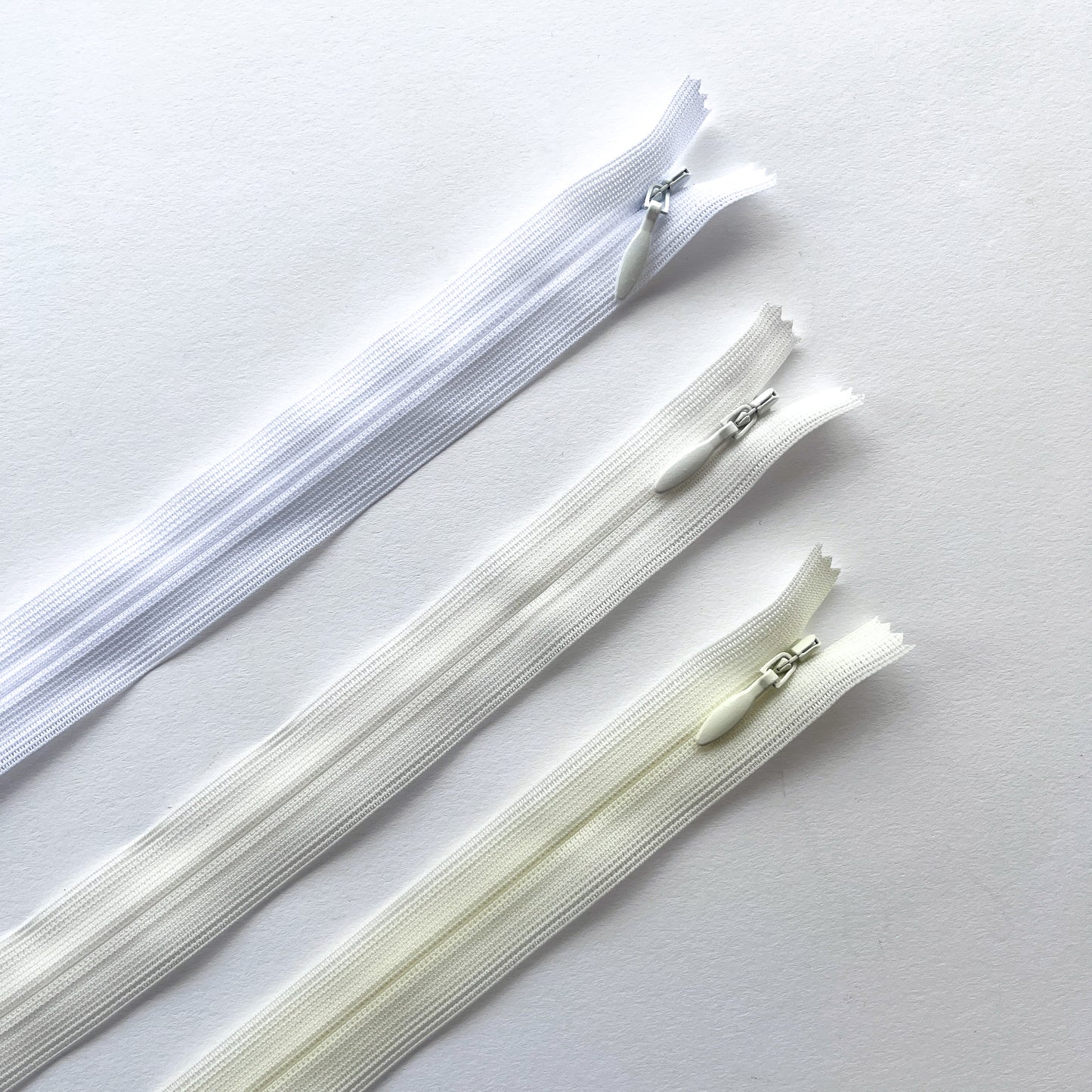 Set of white and ivory zippers on a light gray background