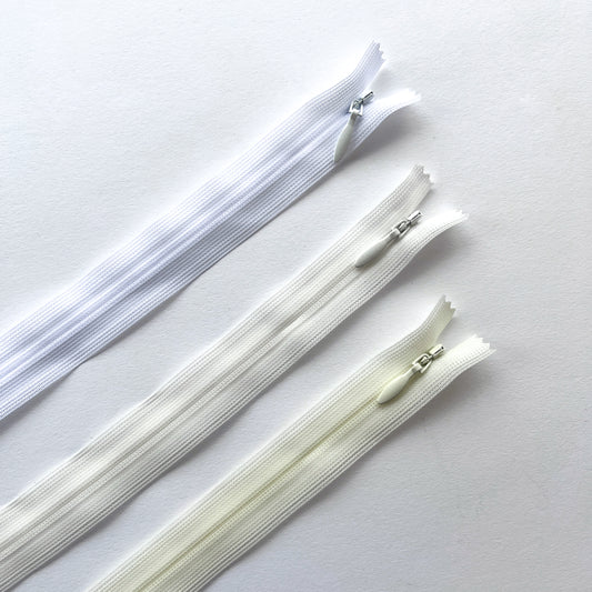 Set of white and ivory zippers on a light gray background