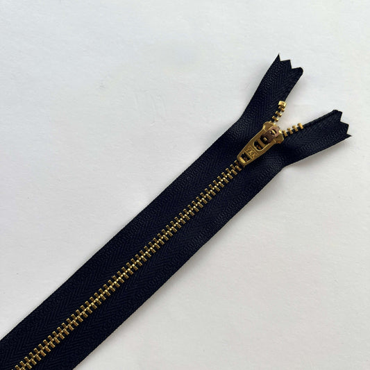 close up of YKK  jeans zip with metal teeth and auto-lock puller in black with gold teeth