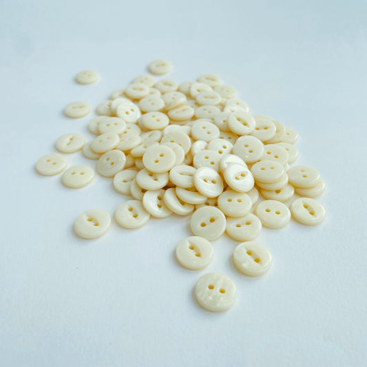 Fisheye Codelite Dairy Shirt Buttons - Kleins Haberdashery, a pile of plastic free Natural Pearlescent buttons made from milk on a white background