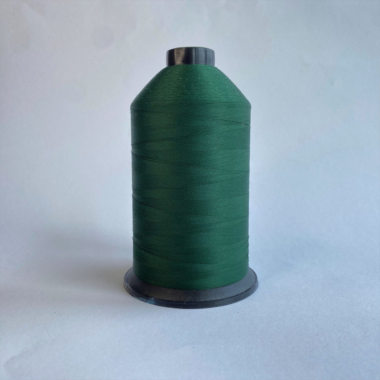 Spool of green thread on a white background