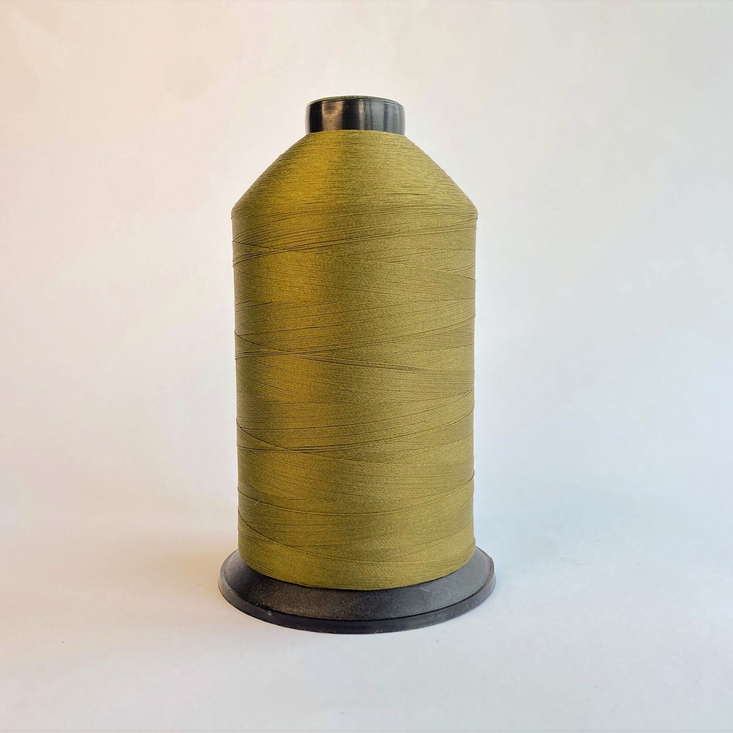 Spool of Dark Olive green sewing thread on a light background