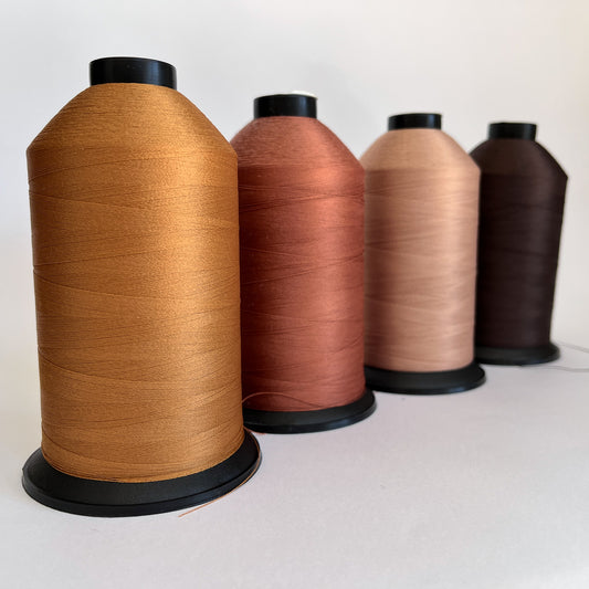 Four spools of brown thread on a white background