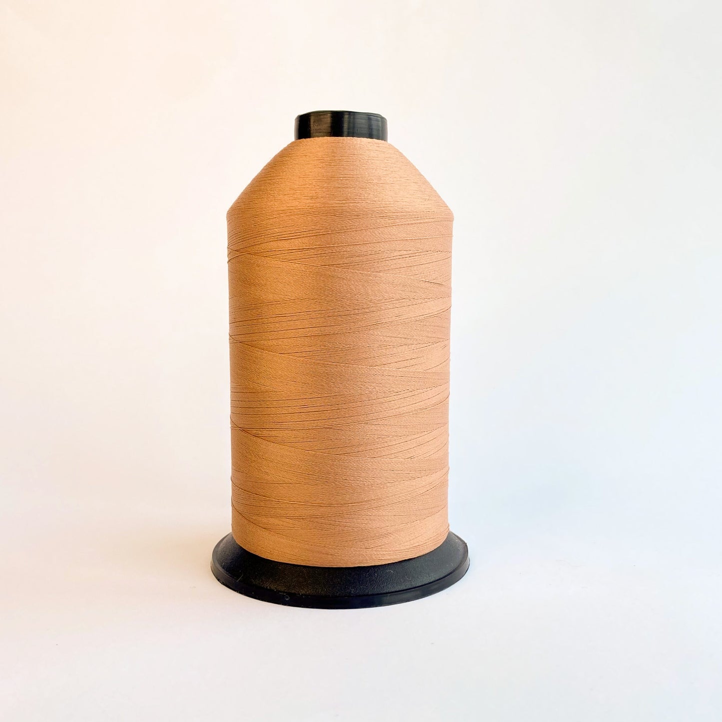 Spool of brown thread on a white background