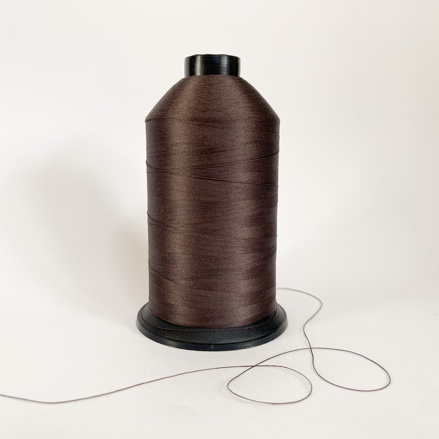 Spool of dark brown 3587 thread on a white background