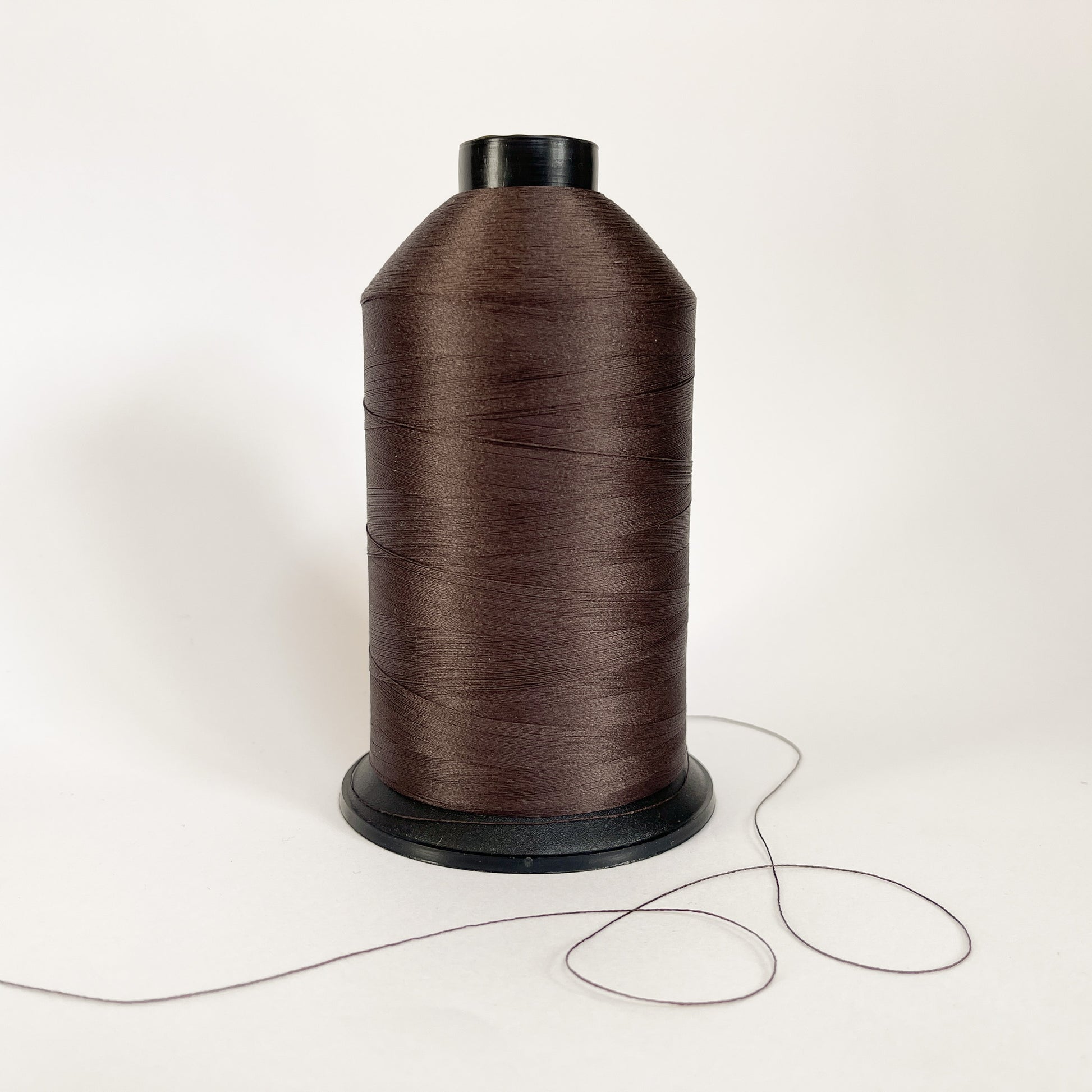 Spool of dark brown 3587 thread on a white background