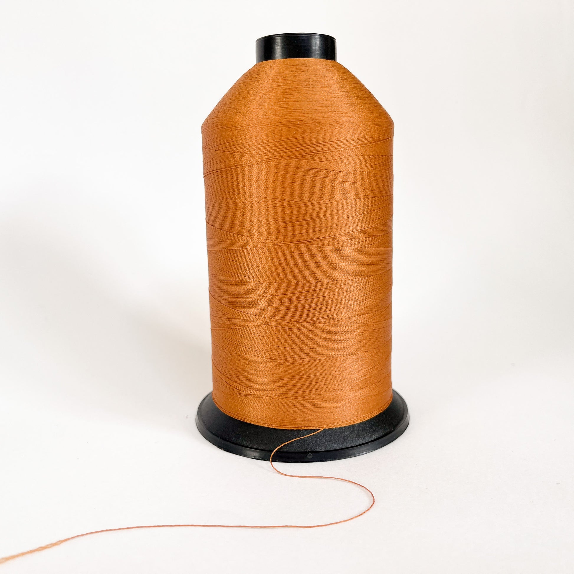 Spool of brown thread on a white background