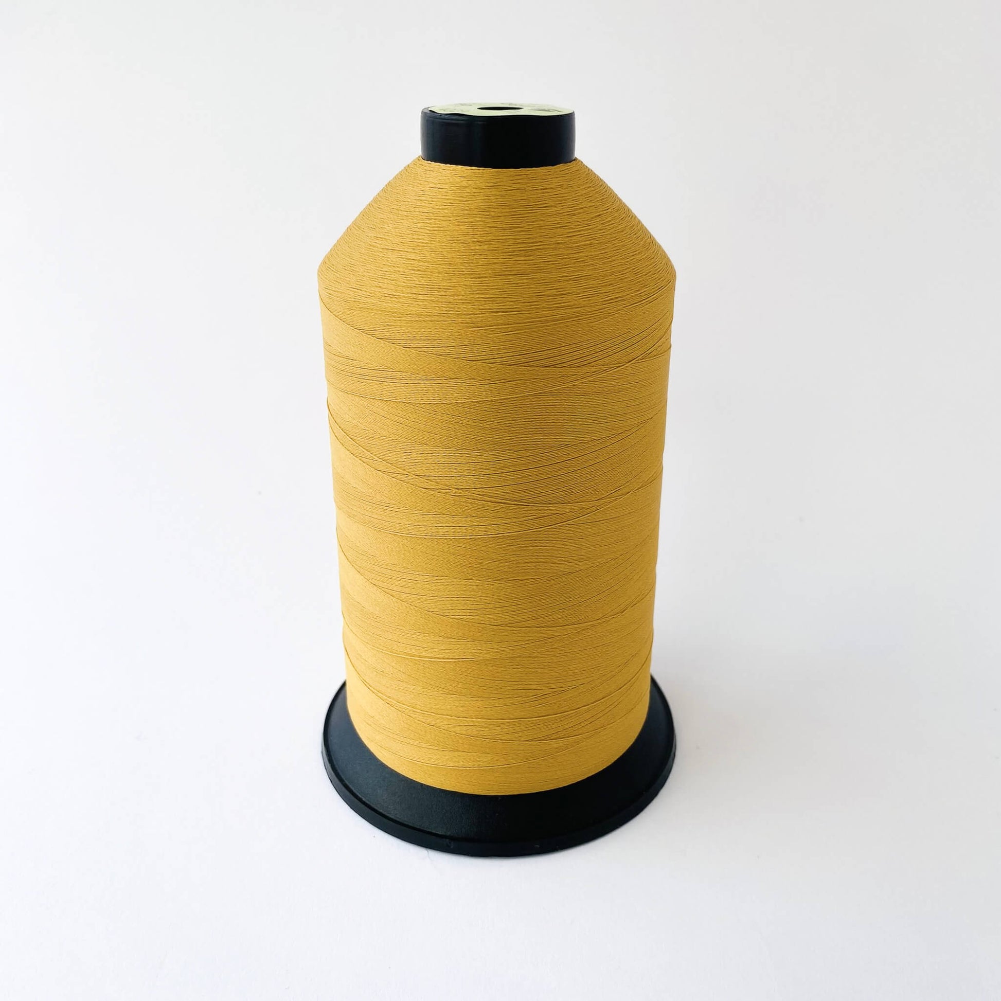Spool of mustard 4029 thread on a white background