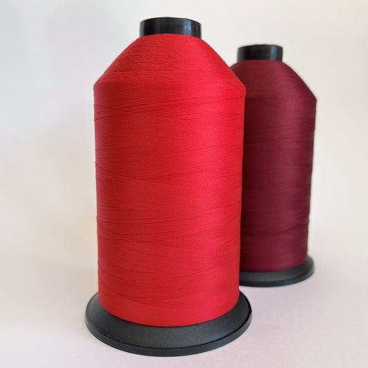 Two spools of red thread on a white background