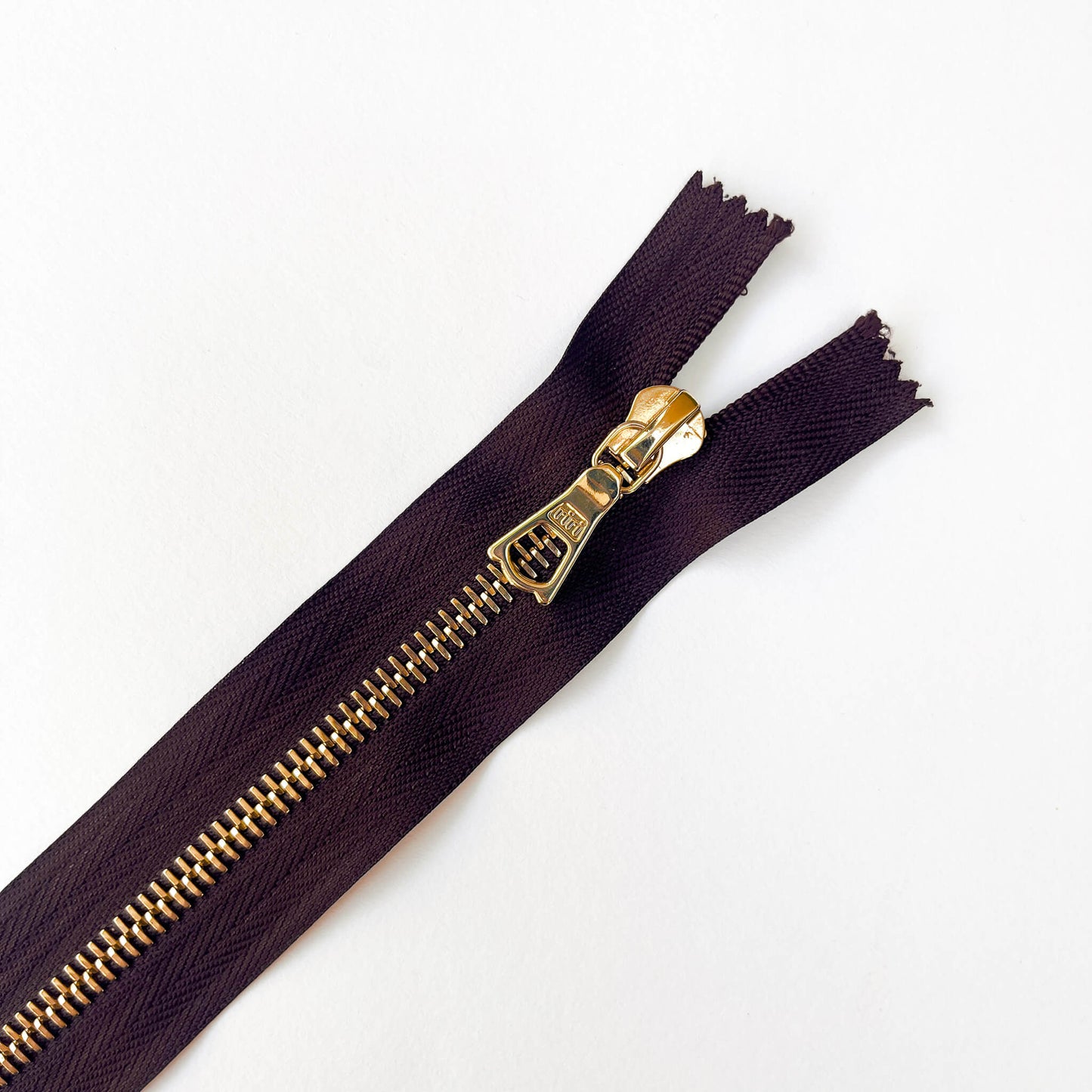 close up of Dark Plum, dark purple  RiRi #6 Metal Zip - 17cm  by RiRi with gold metal teeth and decorative puller - Kleins Haberdashery