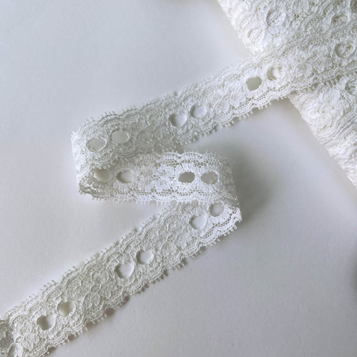 Close-up of white scalloped Ribbon Slot Lace with eyelets