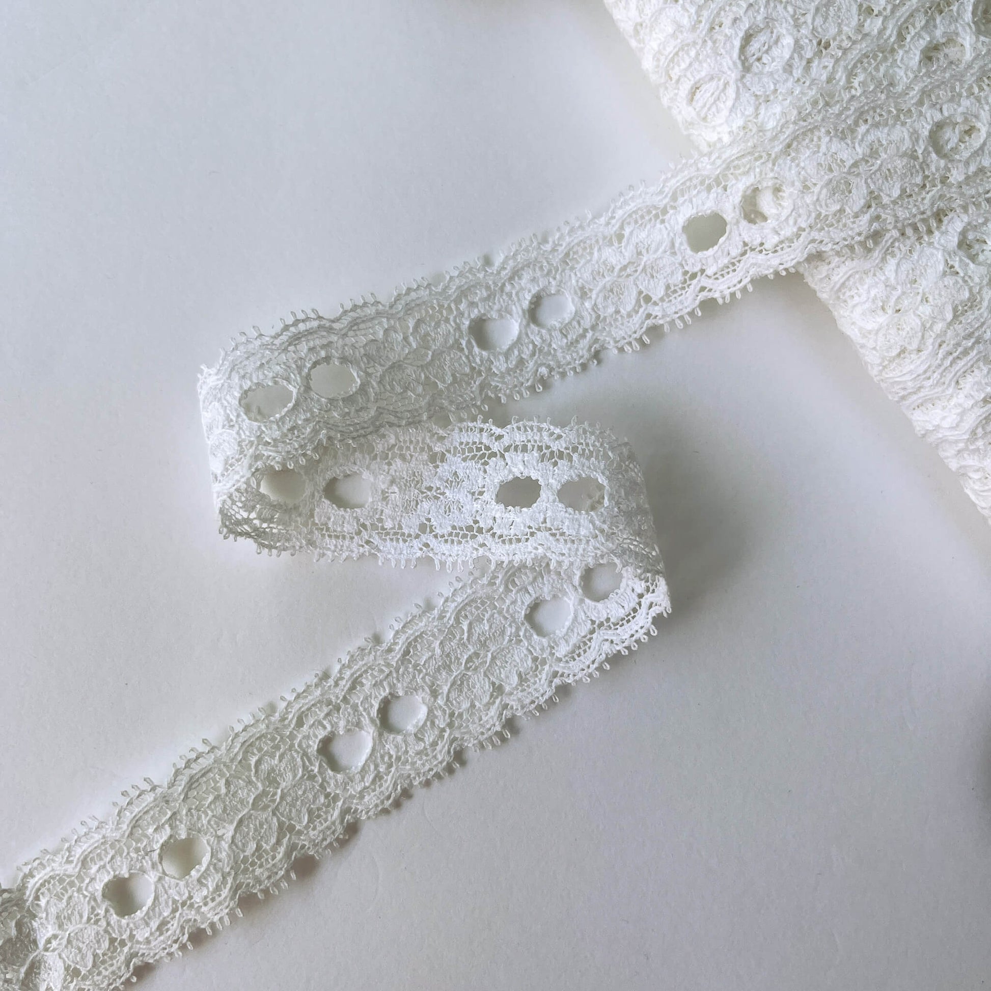 Close-up of white scalloped Ribbon Slot Lace with eyelets
