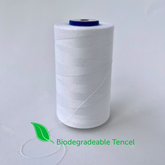 Spool of white yarn with a green leaf icon and 'Biodegradable Tencel' text on a light gray background