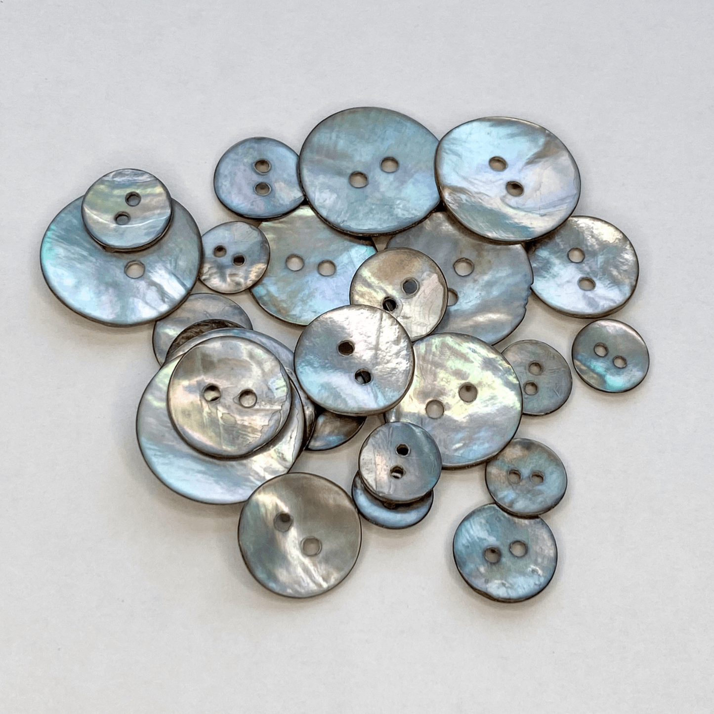 Smoke Grey Akoya shell buttons with a beautiful iridescent sheen. Also known as Mother of Pearl or Agoya shell, in four sizes from 10mm to 15mm.
 - Kleins Haberdashery