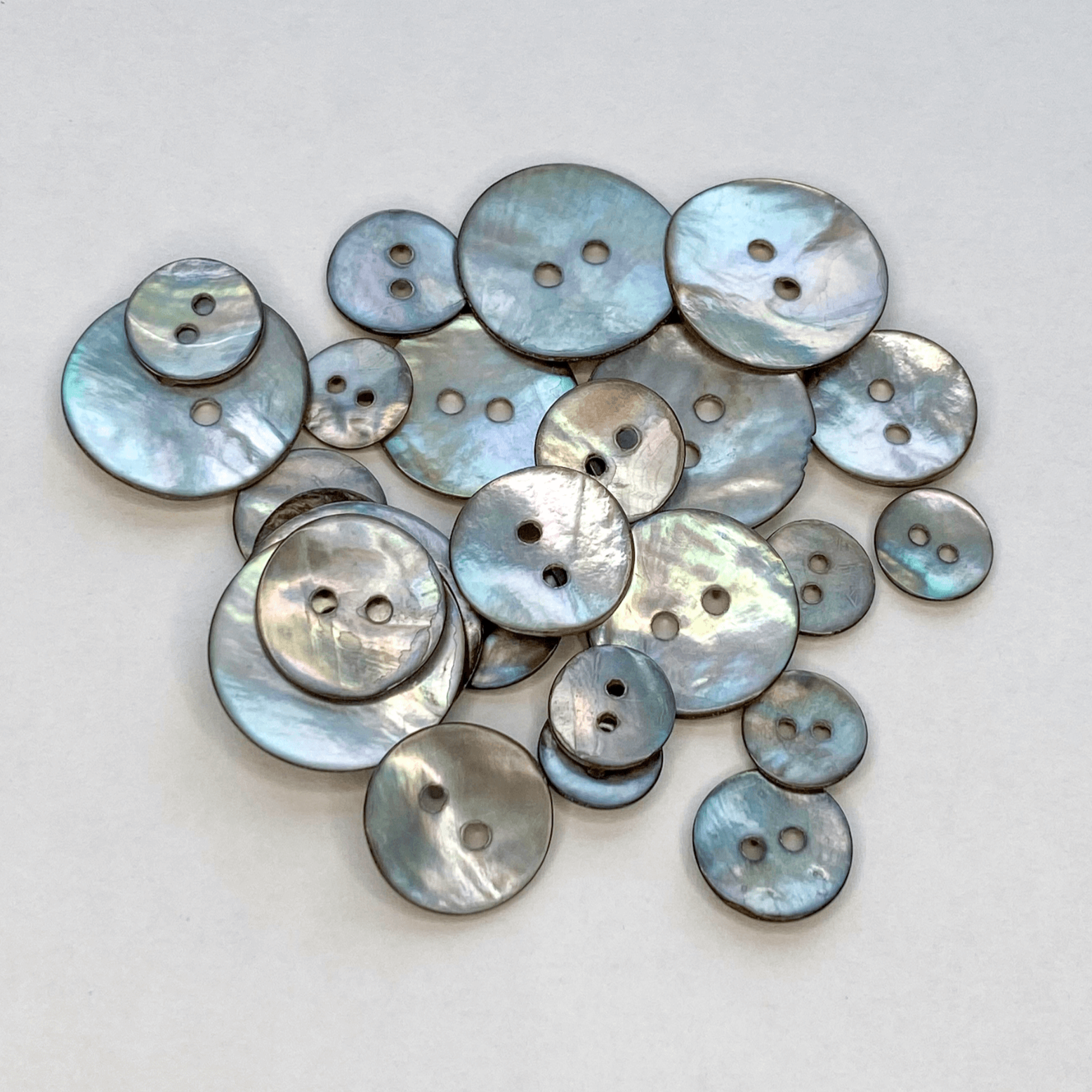 Smoke Grey Akoya shell buttons with a beautiful iridescent sheen. Also known as Mother of Pearl or Agoya shell, in four sizes from 10mm to 15mm.
 - Kleins Haberdashery