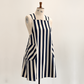 A Japanese style apron with vertical navy blue and off-white stripes, displayed on a cream-coloured dress form mannequin against a plain light background.