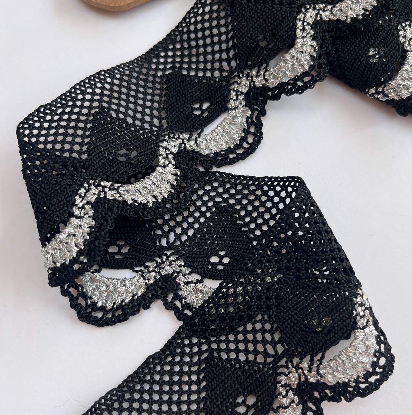 Black lace fabric with silver embellishments on a white background