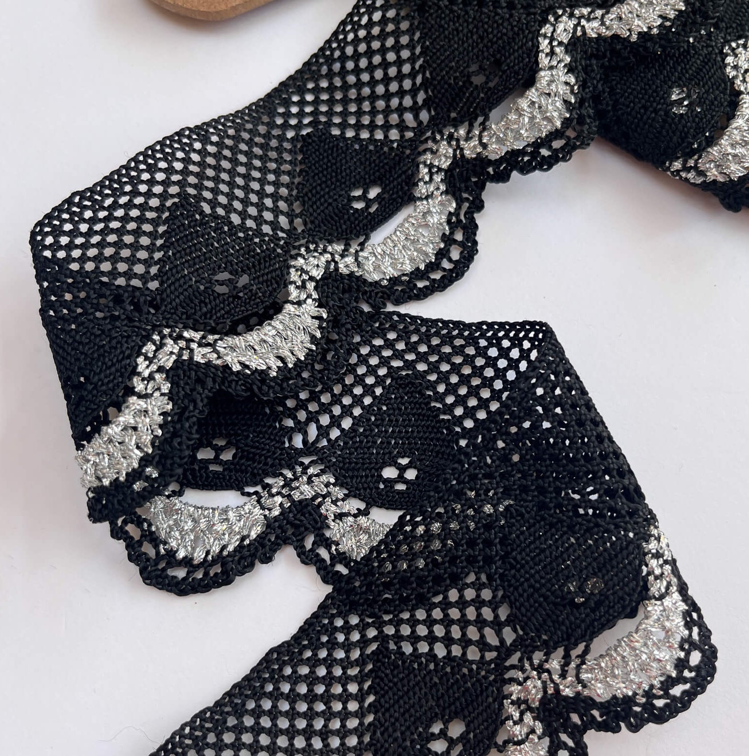 Black lace fabric with silver embellishments on a white background
