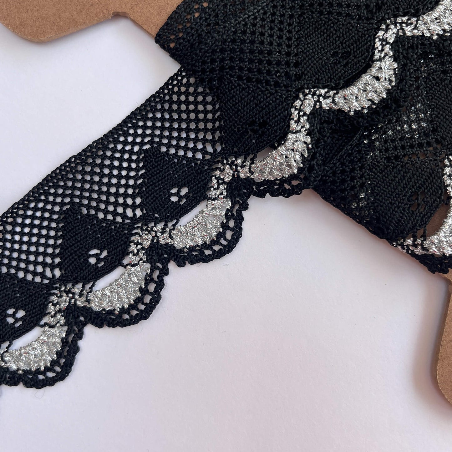 Close-up of black and silver embroidered lace fabric on a white background