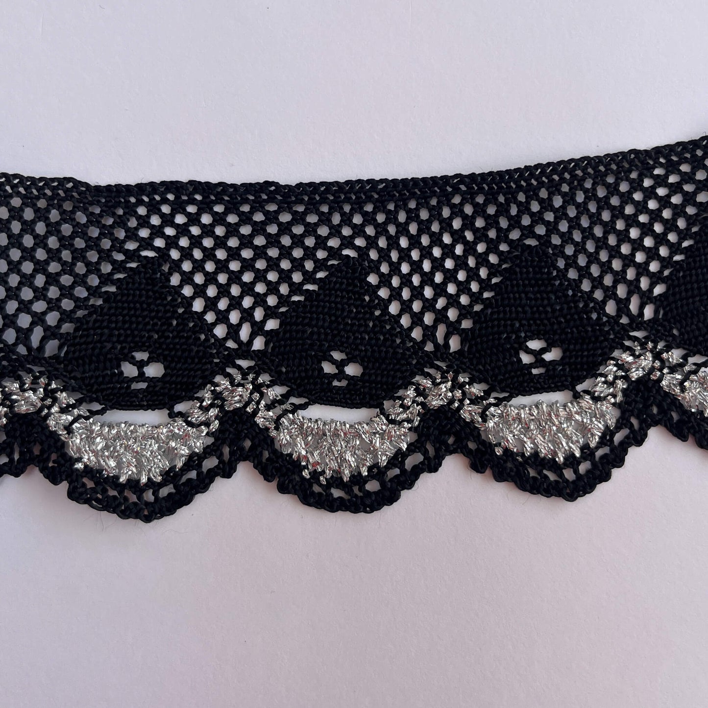 Black lace trim with silver on a white background