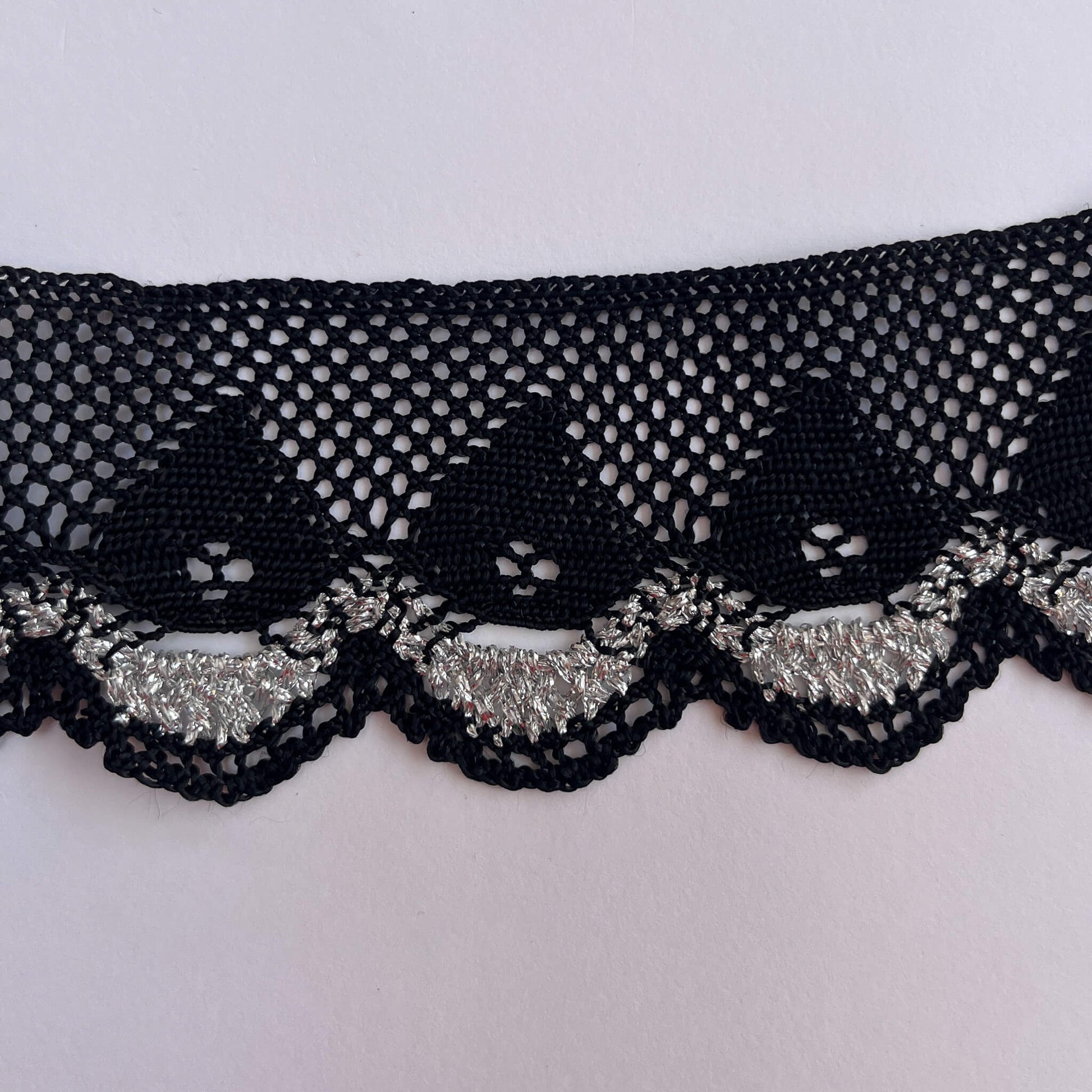Black lace trim with silver on a white background