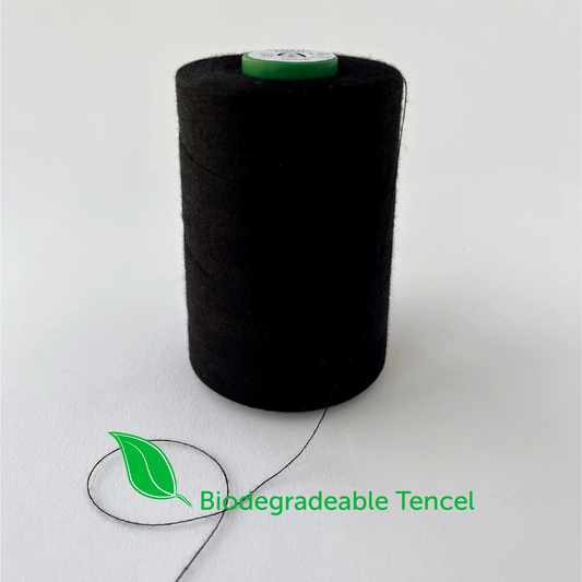 A large spool of black Tencel biodegradable sewing thread on a white background