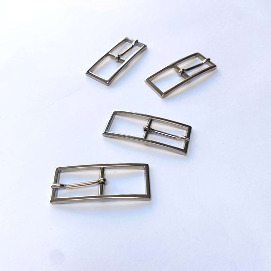 Four silver rectangular buckles with central prong on a white background