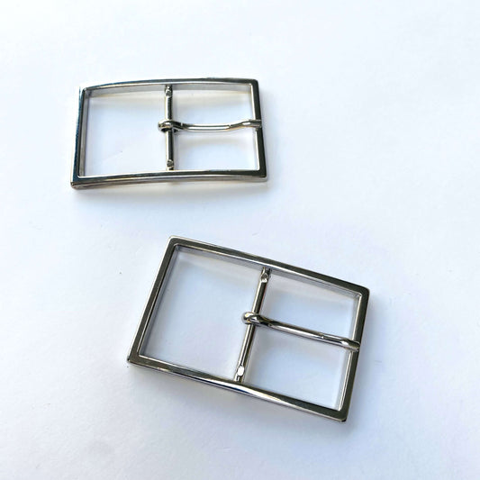 Two silver metal buckles on a white background