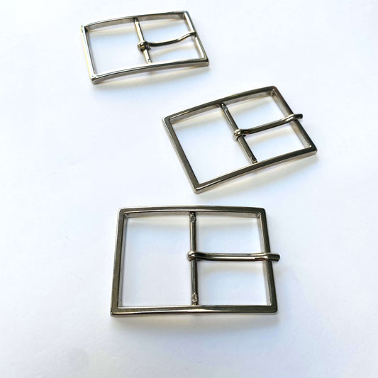 Three large silver metal square prong buckles on a white background