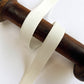 ivory Twill Edge Lingerie Elastic with a fine diagonal herringbone pattern, wrapped around a dark brown wooden dowel on a plain white background.