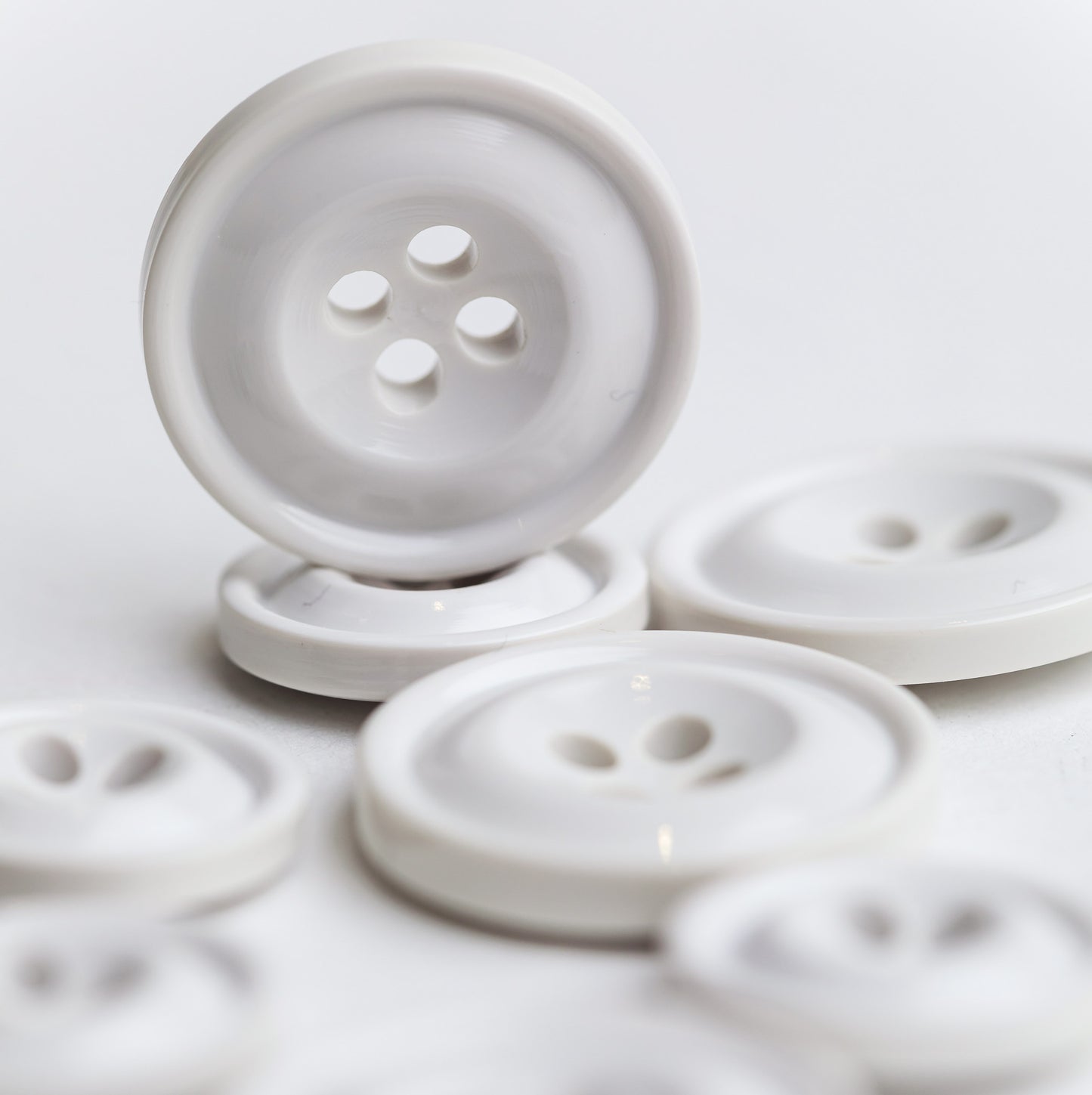 A group of white Codelite buttons of various sizes, with one button standing upright in the foreground on a clean white background. Codelite buttons - plastic free, organic & sustainable.
