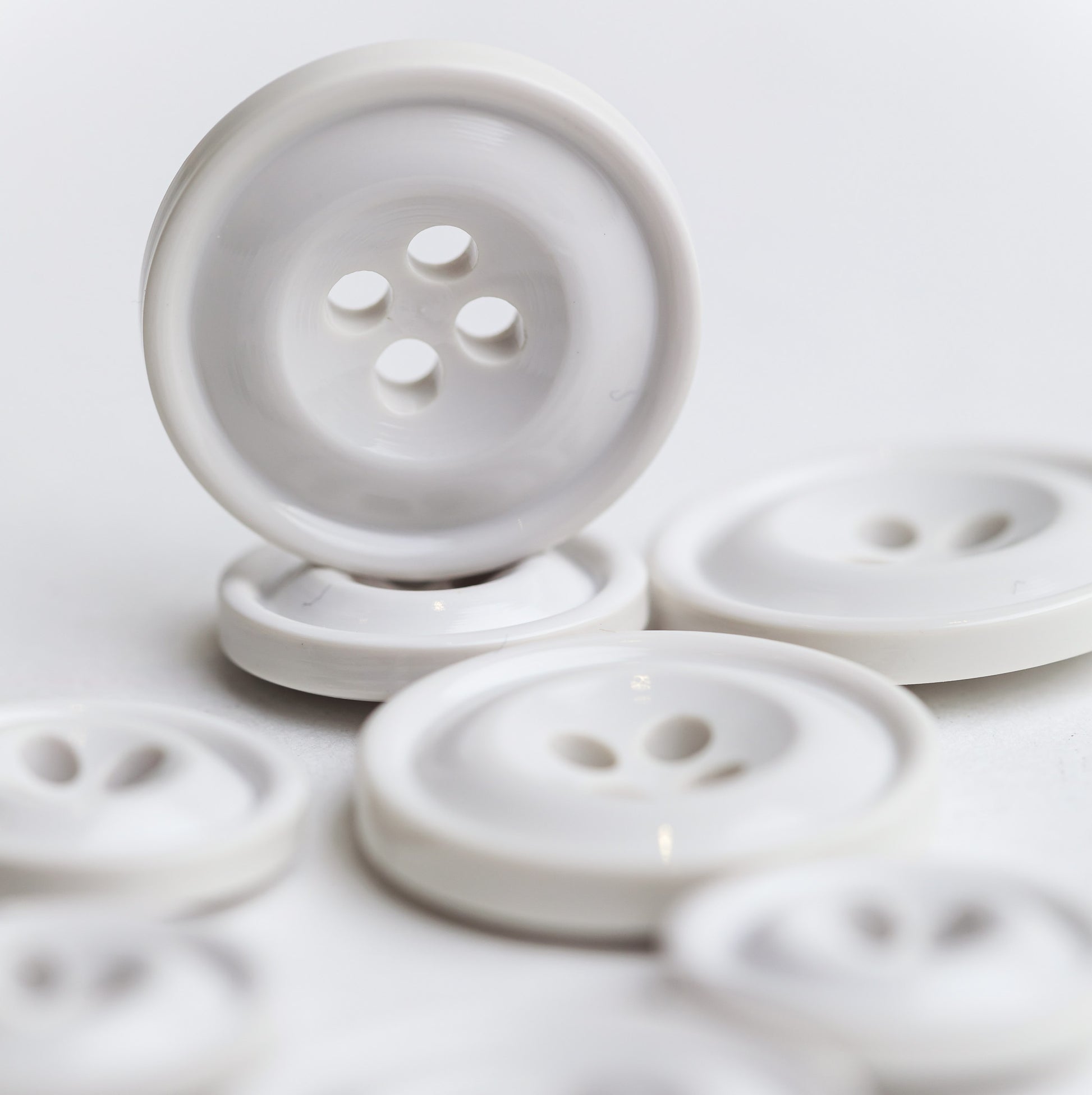 A group of white Codelite buttons of various sizes, with one button standing upright in the foreground on a clean white background. Codelite buttons - plastic free, organic & sustainable.