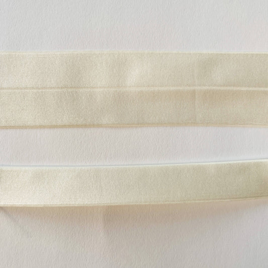 close up of Wide Soft Stretch Satin Fold Over Elastic (FOE) in Ivory, shown flat and folded in half