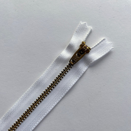 close up of YKK white jeans zip with brass metal teeth and auto-lock puller