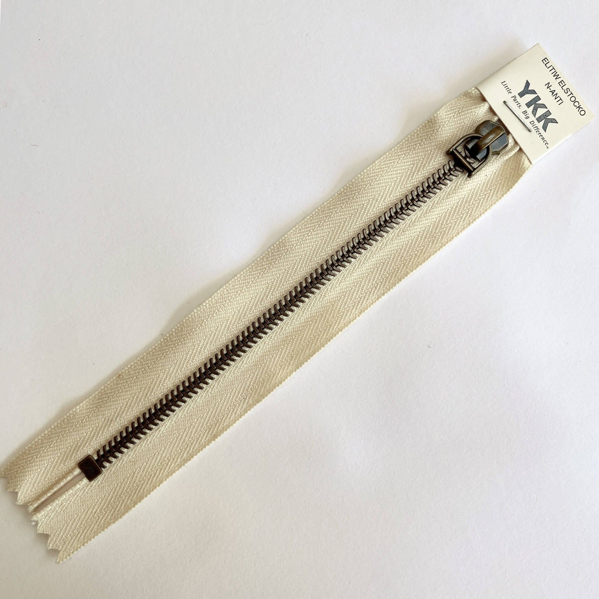 A YKK EXCELLA® Blade closed end zip with ecru tape, 'herringbone' style metal teeth and stirrup puller. 