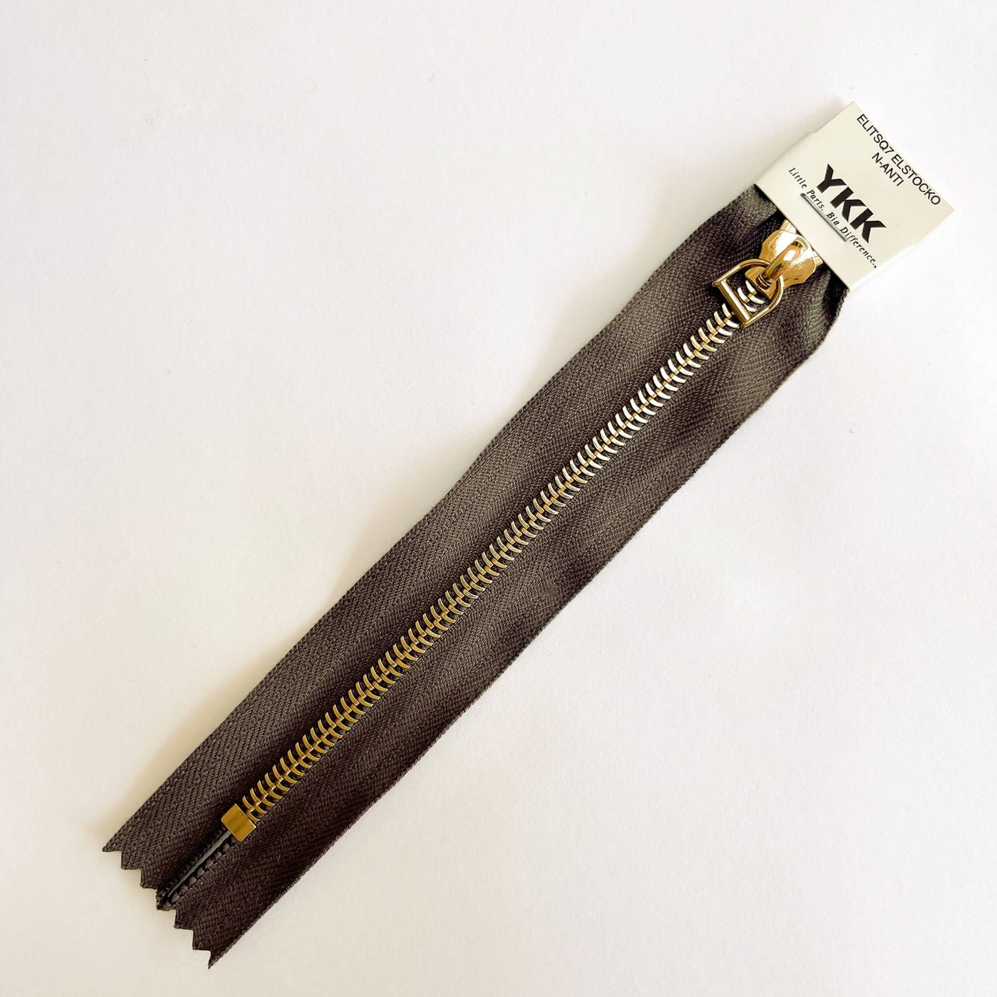 A YKK EXCELLA® Blade closed end zip with brown tape, 'herringbone' style gold metal teeth and stirrup puller. 