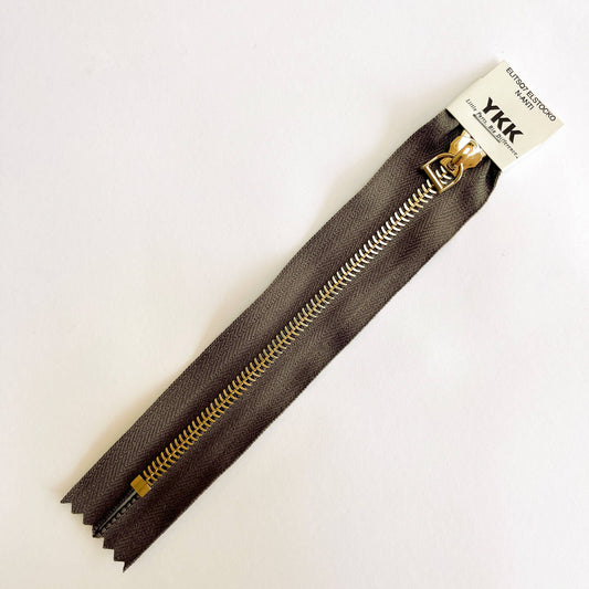 A YKK EXCELLA® Blade closed end zip with brown tape, 'herringbone' style gold metal teeth and stirrup puller. 
