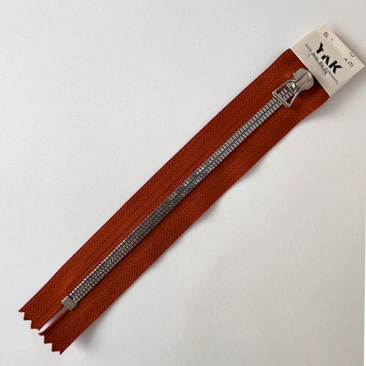 A YKK EXCELLA® Flat closed end zip with Rust tape, flat, smooth style silver metal teeth and stirrup puller. 